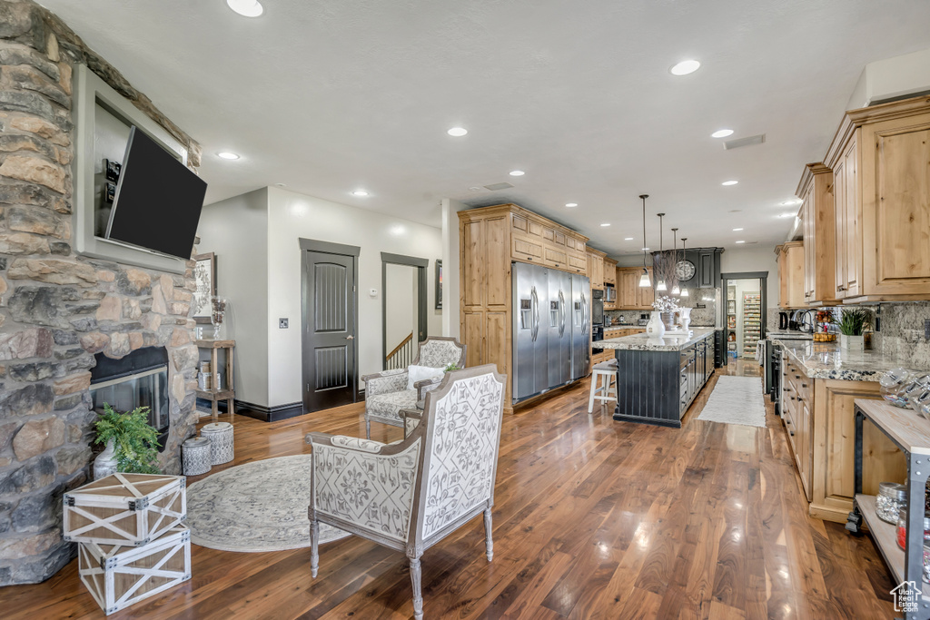 Living area with wood finished floors, recessed lighting, a stone fireplace, and stairway