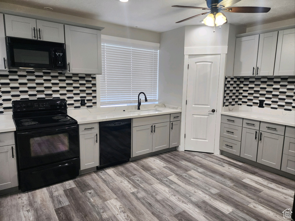 Kitchen with black appliances, gray cabinets, backsplash, and light wood-style flooring
