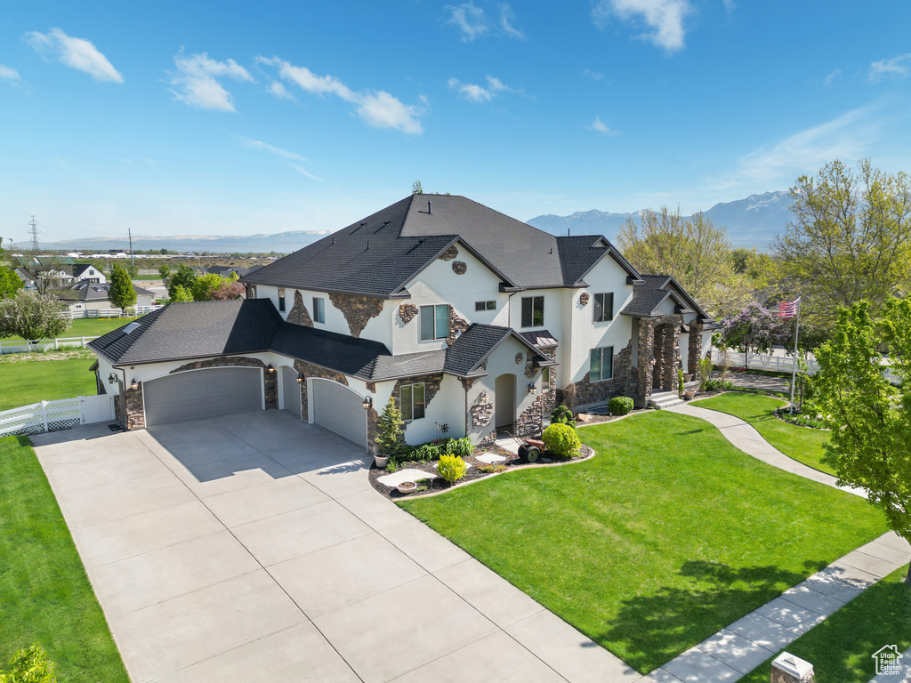 French provincial home with stone siding, a mountain view, driveway, an attached garage, and stucco siding