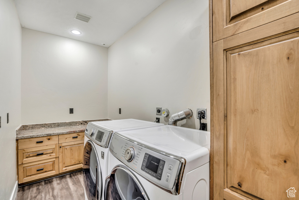 Laundry area featuring washer and dryer, wood finished floors, cabinet space, and recessed lighting