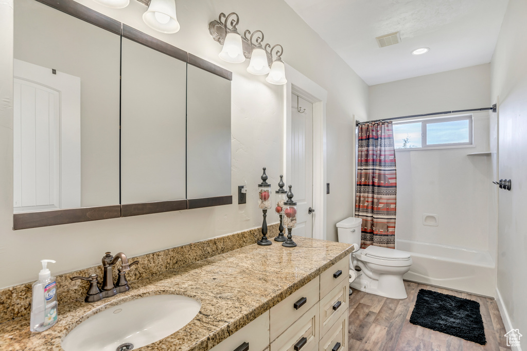 Full bathroom featuring vanity, shower / tub combo, and wood finished floors