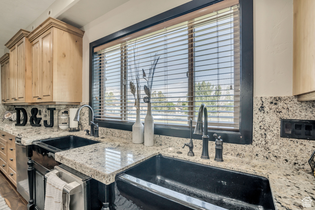 Kitchen featuring light brown cabinetry, tasteful backsplash, healthy amount of natural light, and light stone countertops