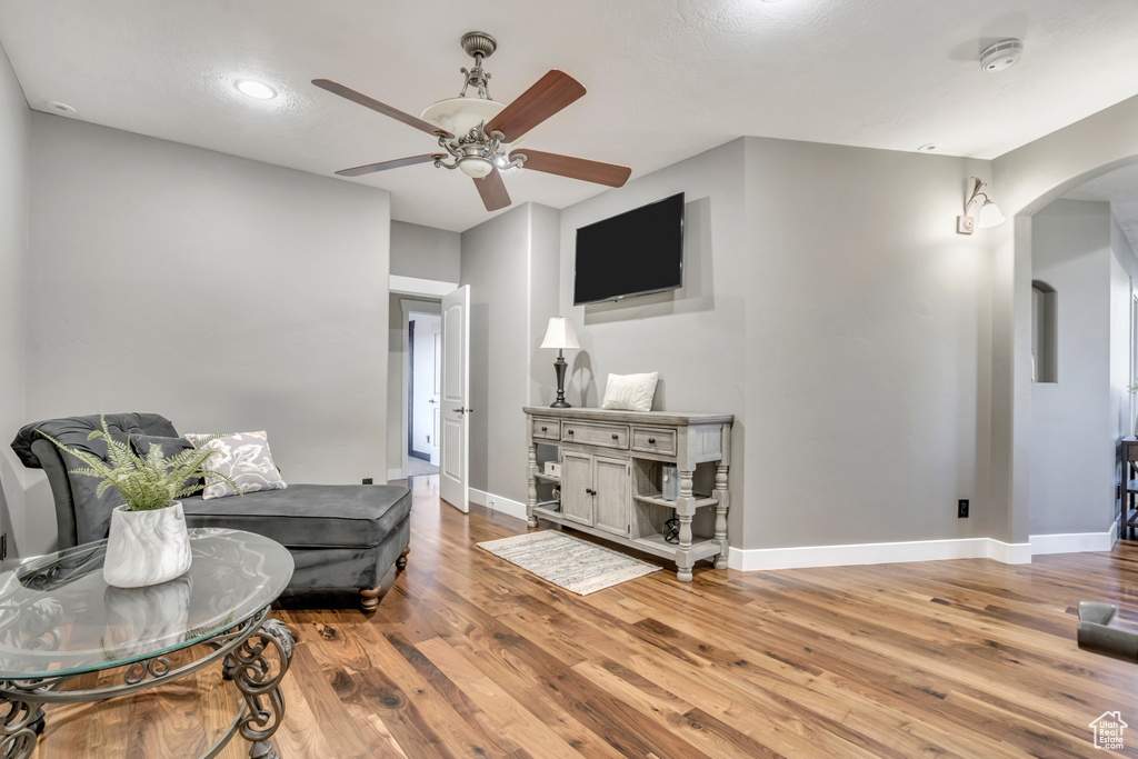 Living area featuring arched walkways, ceiling fan, and wood finished floors