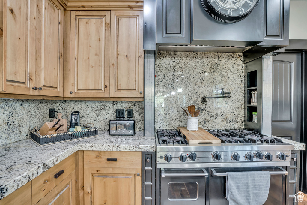 Kitchen featuring double oven range, tasteful backsplash, and range hood