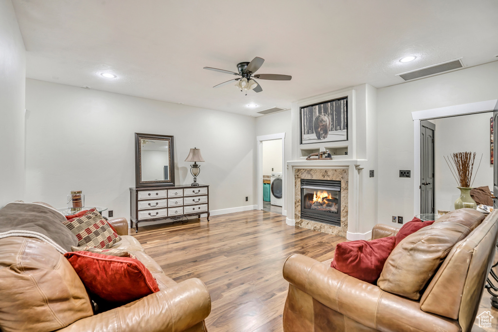 Living room featuring wood finished floors, attic access, washer / dryer, a fireplace, and ceiling fan