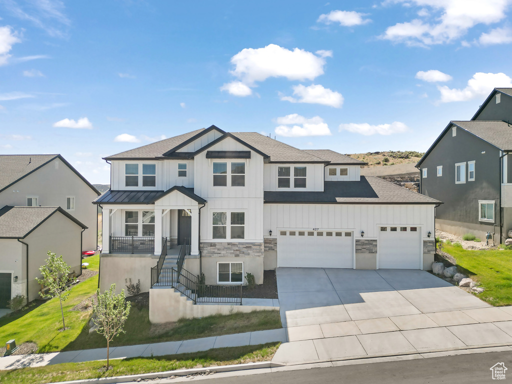 View of front of home with board and batten siding, driveway, stone siding, and a garage