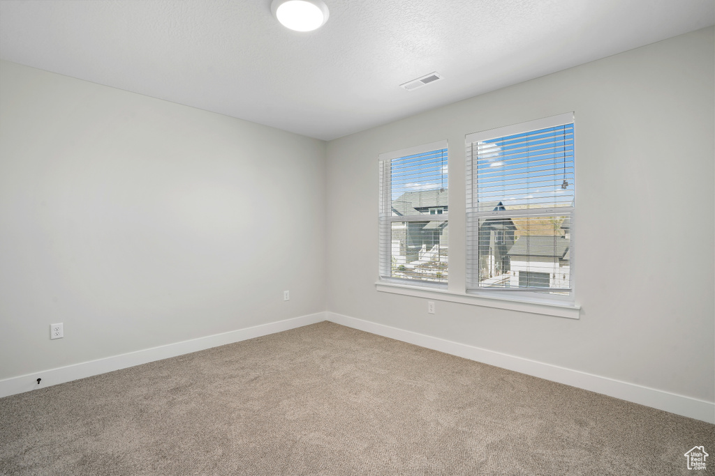 Spare room featuring carpet flooring and baseboards