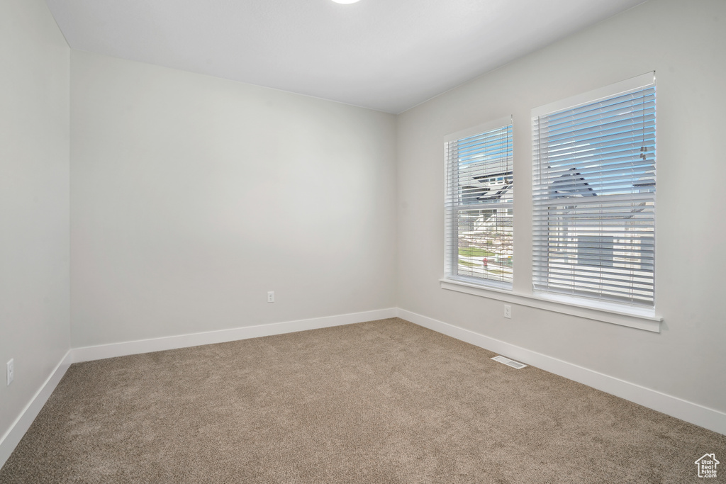 Carpeted spare room featuring baseboards