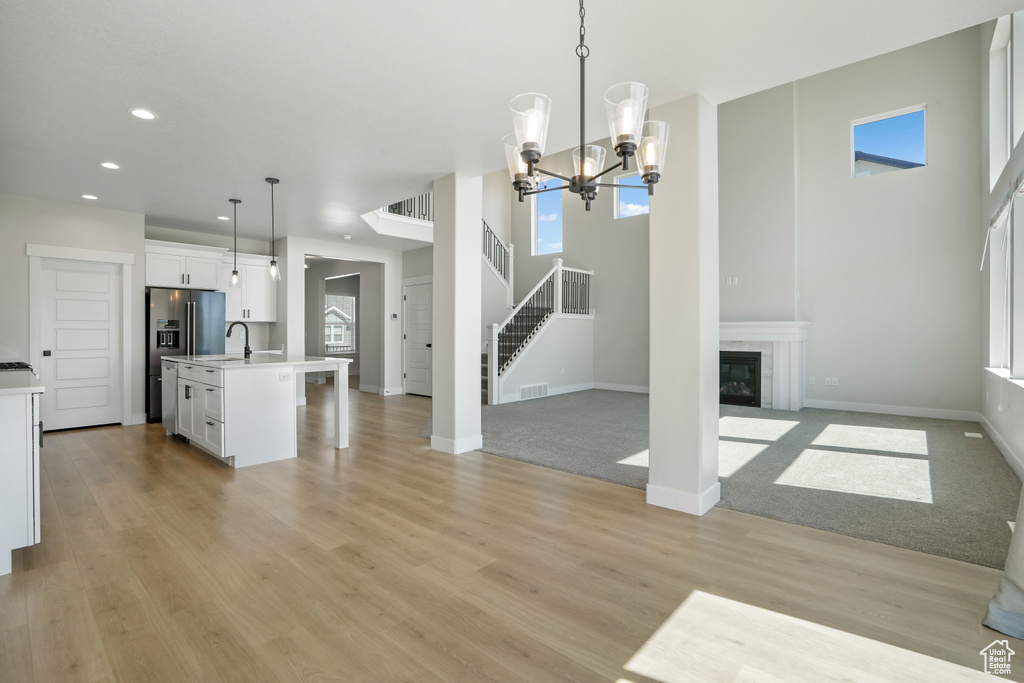 Kitchen with open floor plan, recessed lighting, high end refrigerator, pendant lighting, and white cabinets