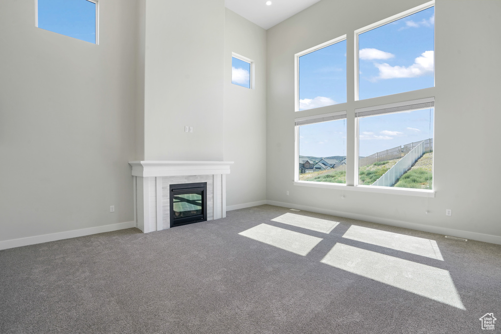 Unfurnished living room featuring a fireplace, a high ceiling, and carpet flooring