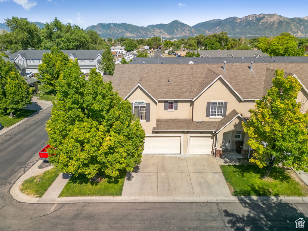 View of front facade featuring stucco siding, an attached garage, driveway, a mountain view, and a residential view