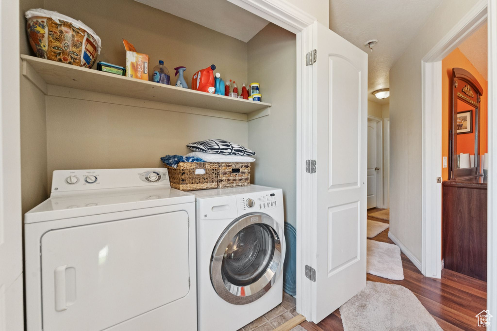 Laundry area featuring independent washer and dryer and wood finished floors