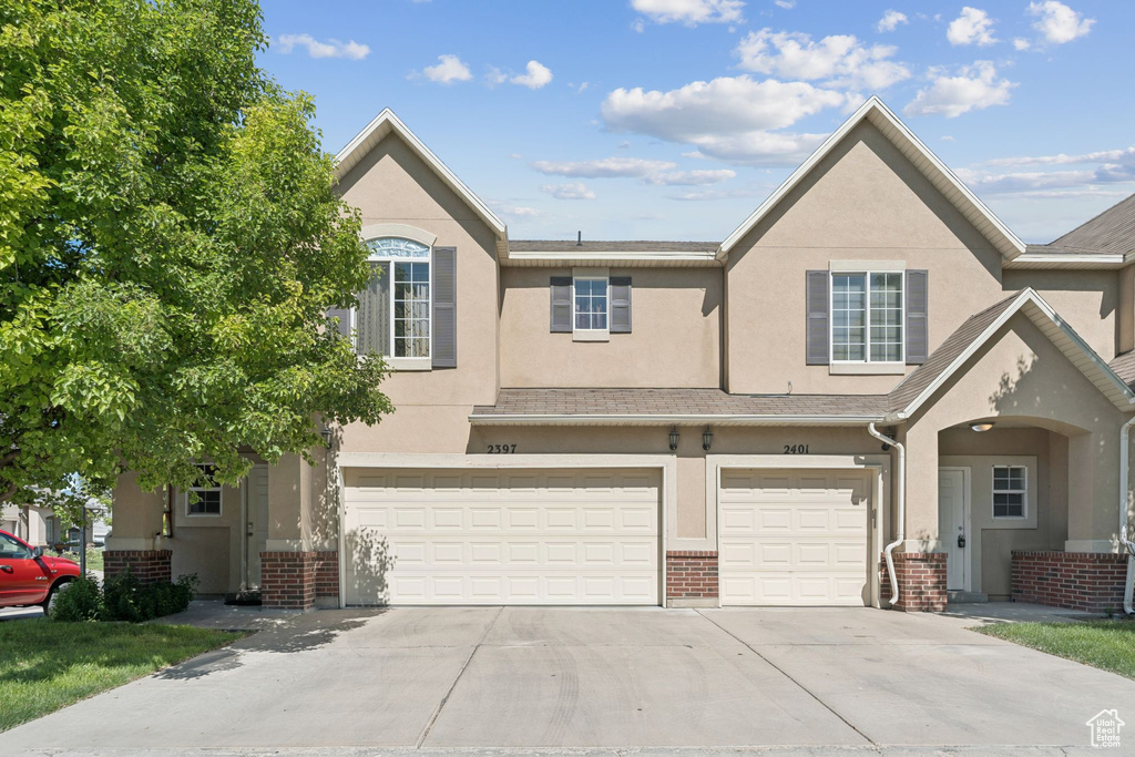 Multi unit property featuring stucco siding, an attached garage, driveway, and brick siding