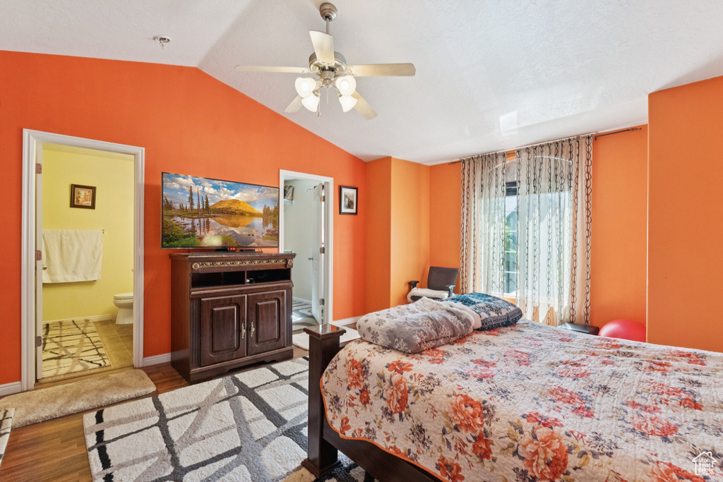 Bedroom featuring wood finished floors, lofted ceiling, ensuite bath, and a ceiling fan