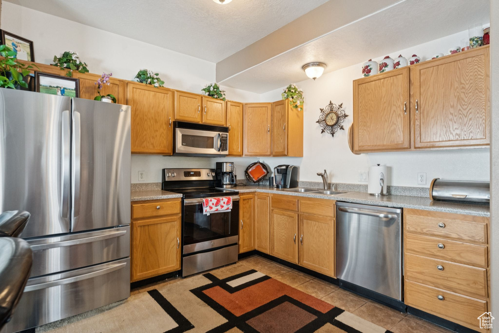 Kitchen with appliances with stainless steel finishes, light countertops, and light tile patterned flooring
