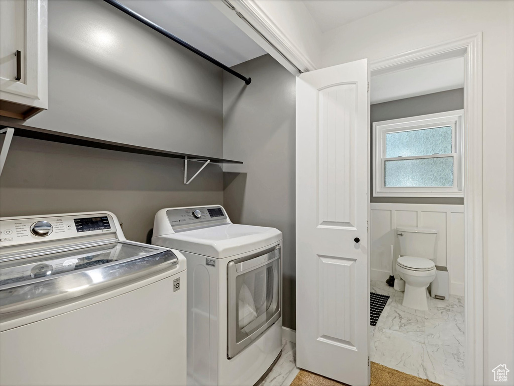 Laundry room with washer and clothes dryer and light marble finish flooring