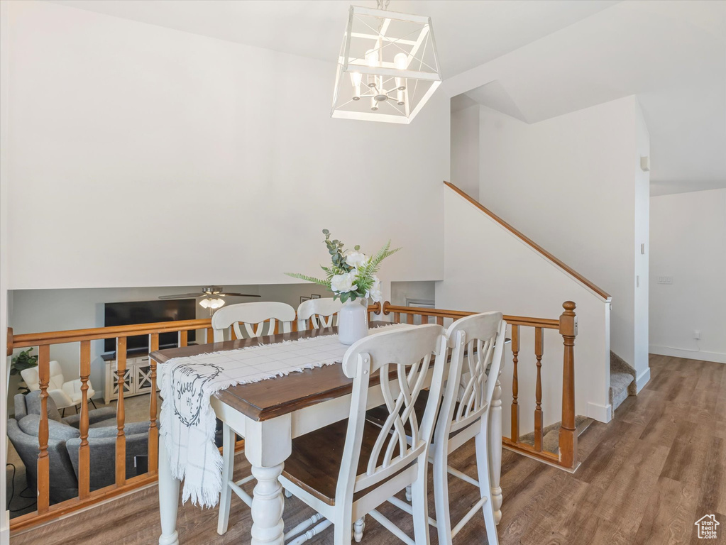 Dining space featuring wood finished floors, stairs, a chandelier, and lofted ceiling