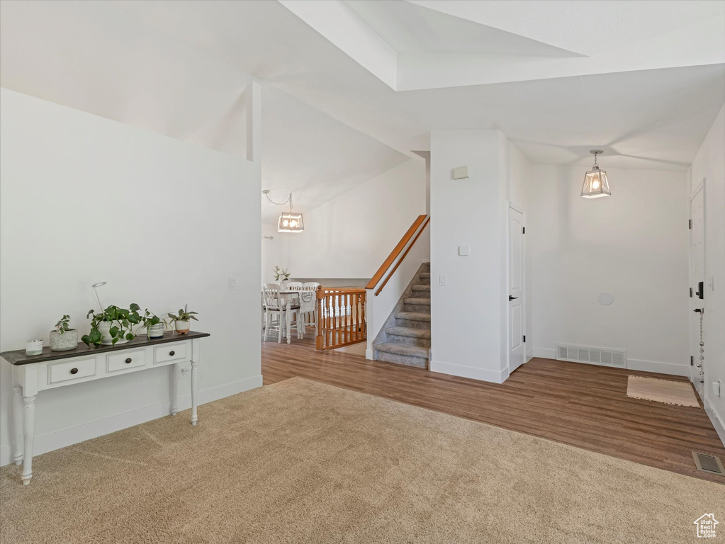 Entrance foyer featuring carpet floors, stairway, and wood finished floors