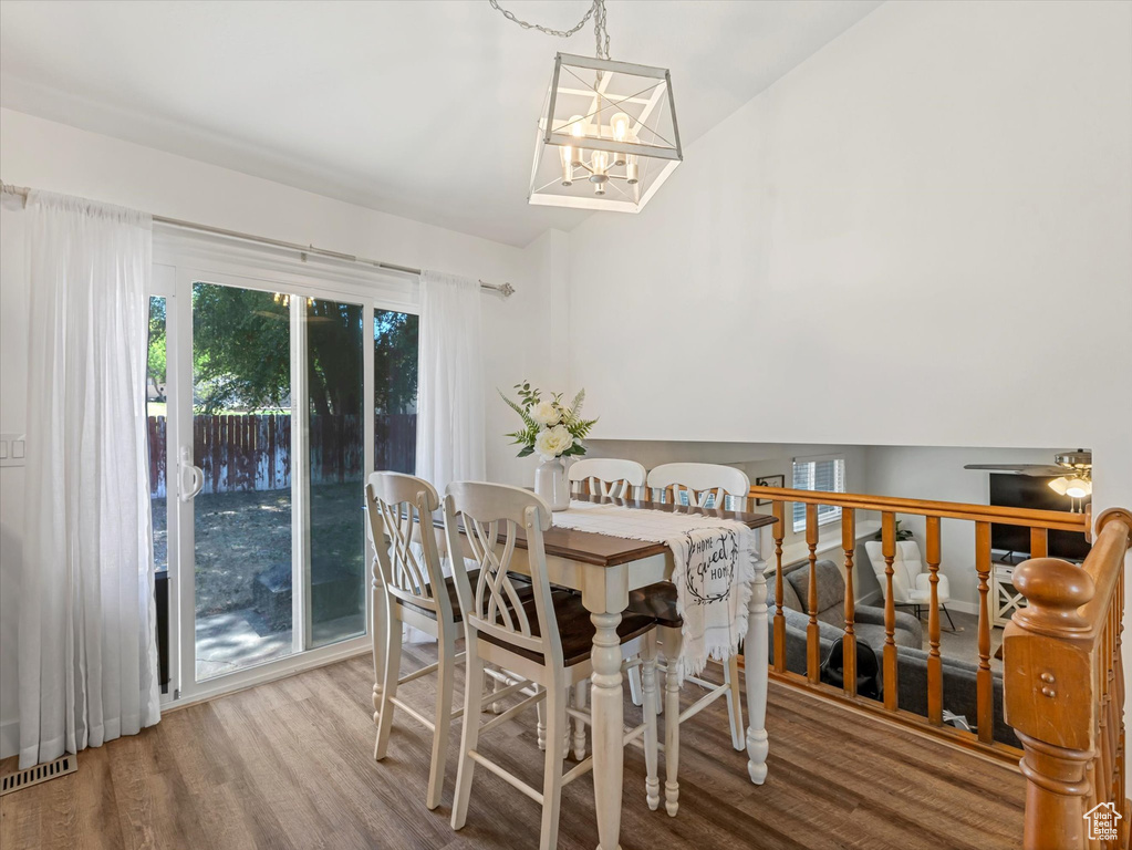 Dining area with wood finished floors, a chandelier, and vaulted ceiling
