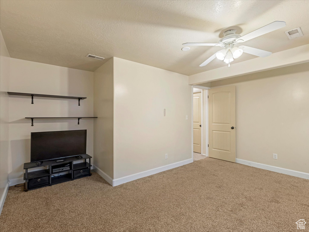 Unfurnished living room with carpet flooring, ceiling fan, and a textured ceiling