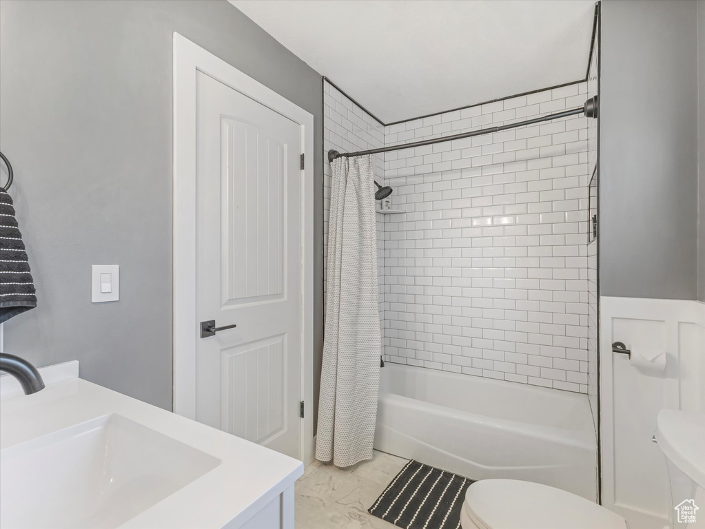 Bathroom with shower / tub combo with curtain, vanity, and marble look tile flooring