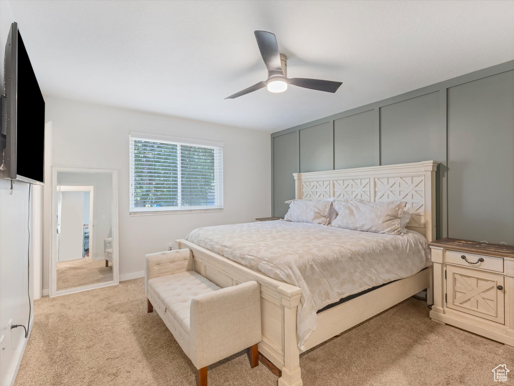 Bedroom with light carpet, ceiling fan, and a decorative wall