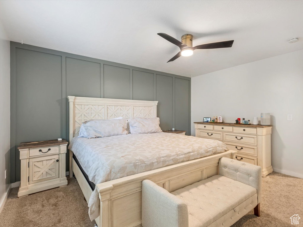Bedroom with a decorative wall, light colored carpet, and ceiling fan