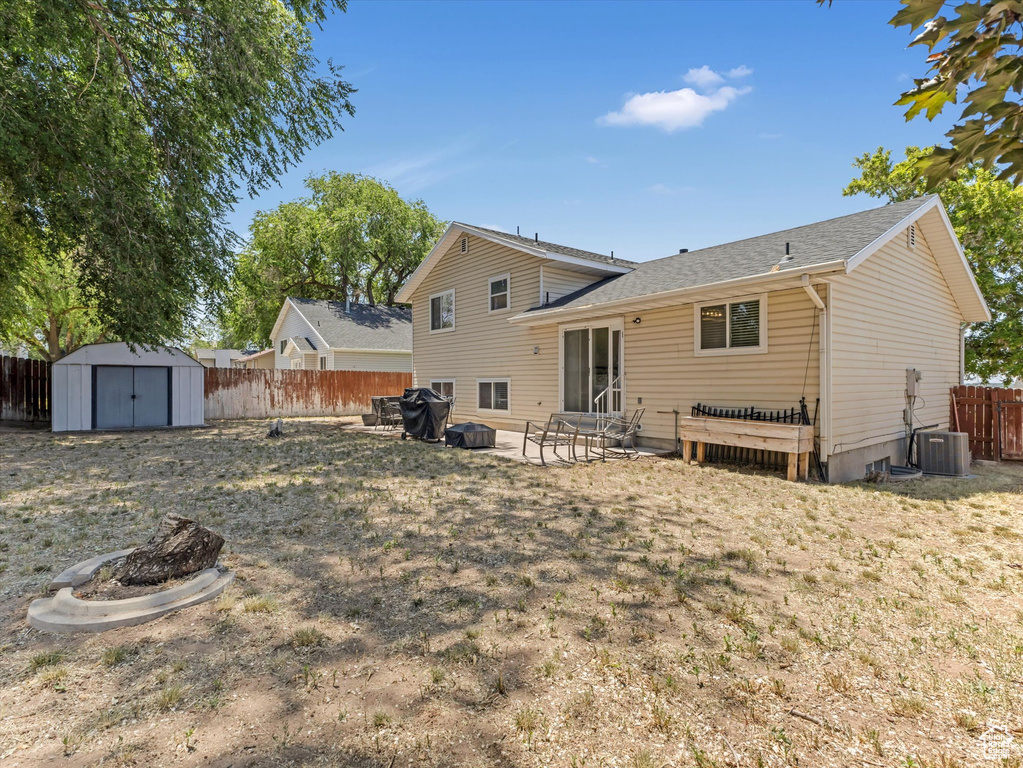 Rear view of property with a fire pit, a fenced backyard, a storage shed, and a patio area