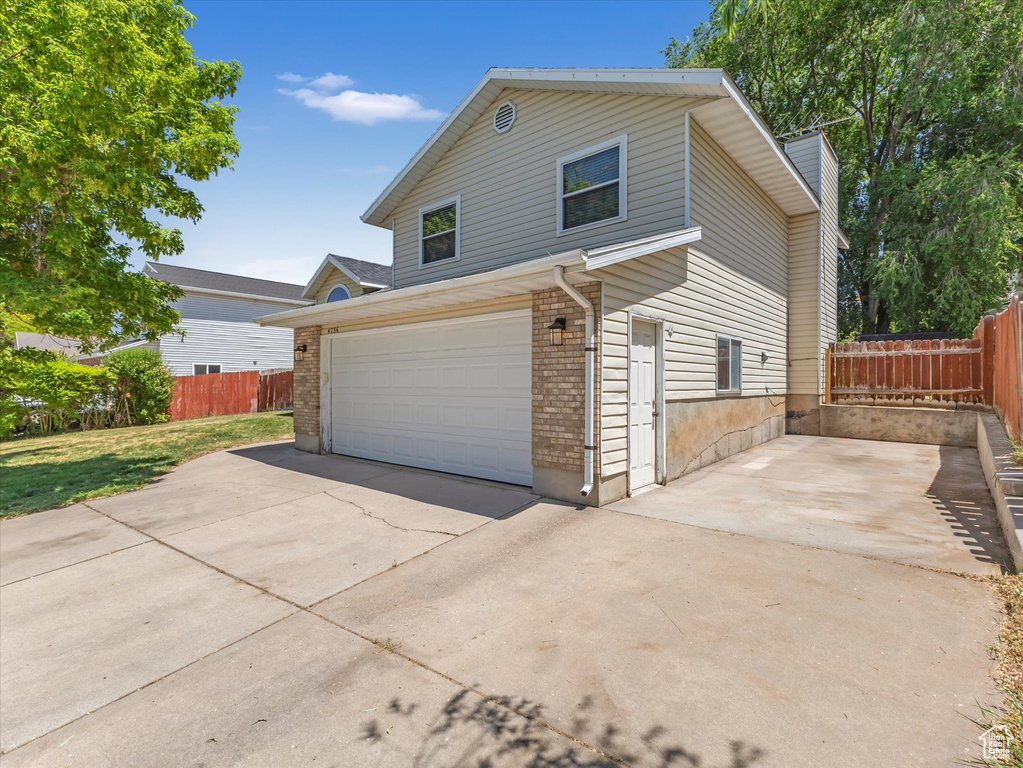 View of front of property with concrete driveway, an attached garage, a chimney, and brick siding