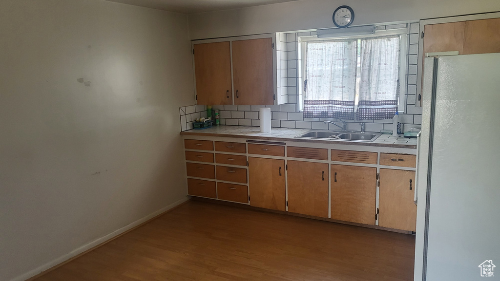 Kitchen with freestanding refrigerator, backsplash, and wood finished floors