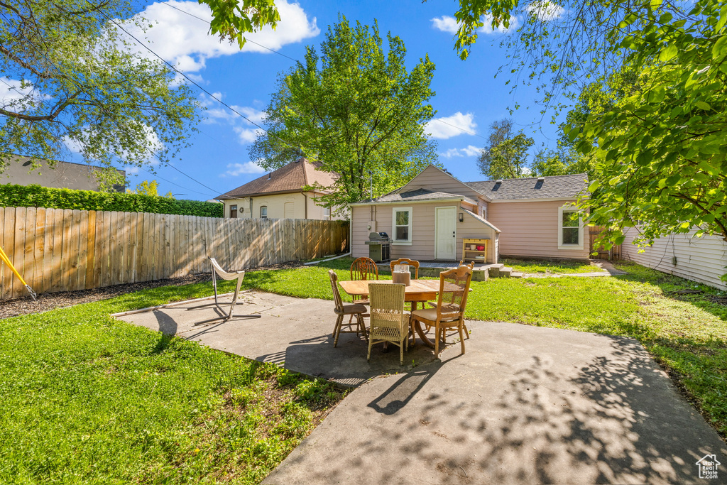 Fenced backyard featuring a patio, area for grilling, and an outbuilding