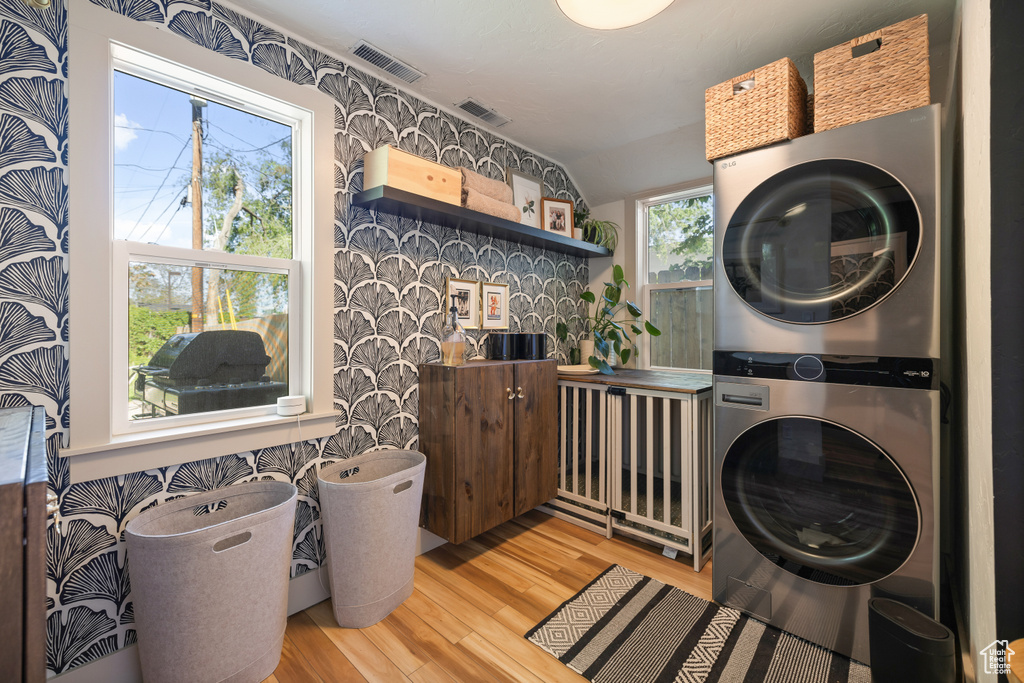 Laundry area with stacked washer and clothes dryer and light wood-style floors