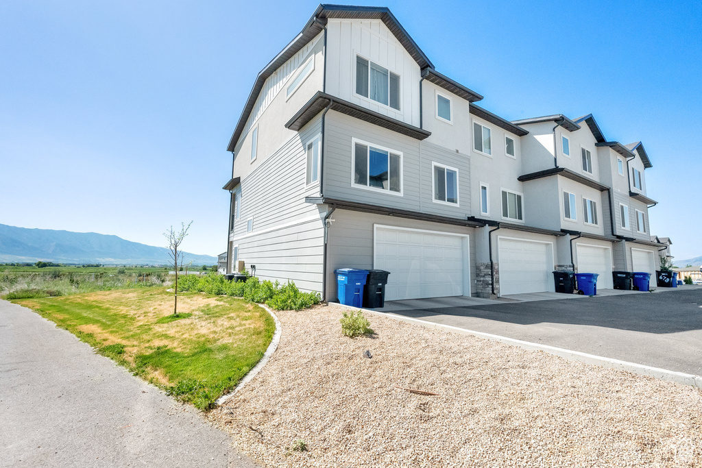 View of side of home featuring an attached garage, a mountain view, and driveway