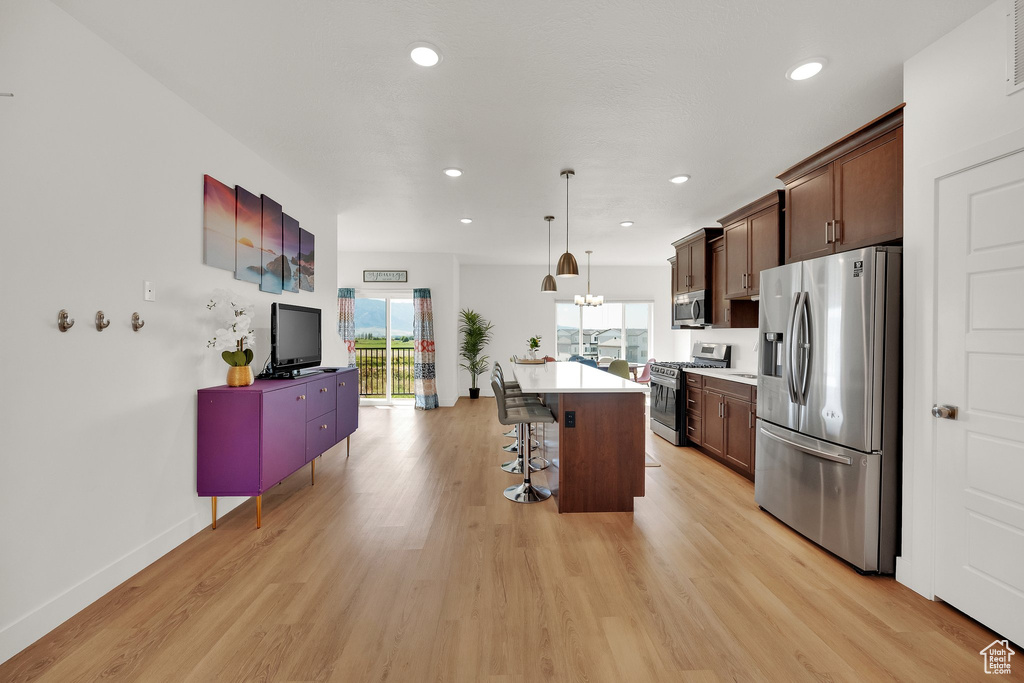 Kitchen featuring appliances with stainless steel finishes, a breakfast bar area, light wood-style flooring, a center island, and recessed lighting