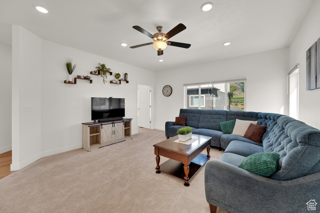 Living area featuring a ceiling fan, light colored carpet, and recessed lighting