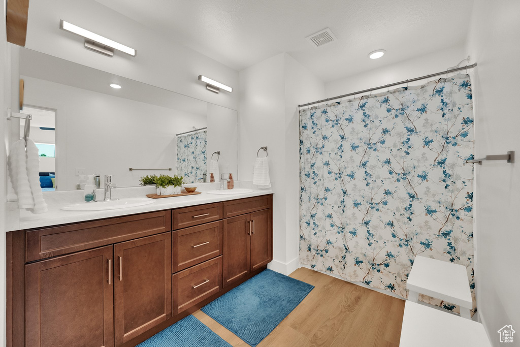 Full bath featuring wood finished floors, double vanity, and a shower with curtain