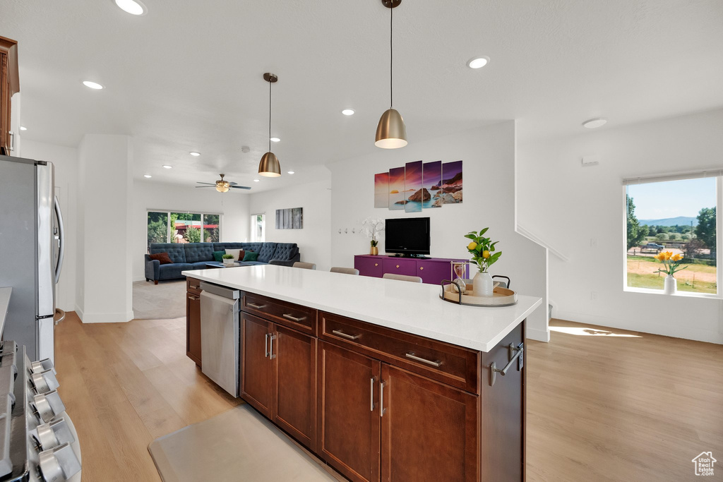 Kitchen with open floor plan, light wood-type flooring, recessed lighting, plenty of natural light, and hanging light fixtures
