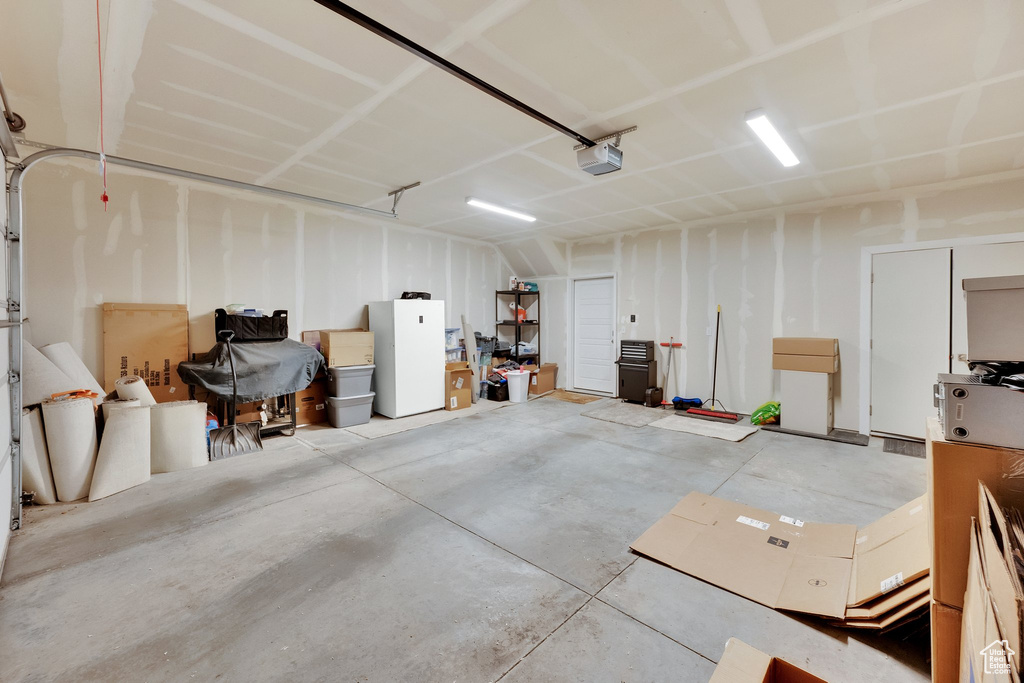 Garage with a garage door opener and freestanding refrigerator