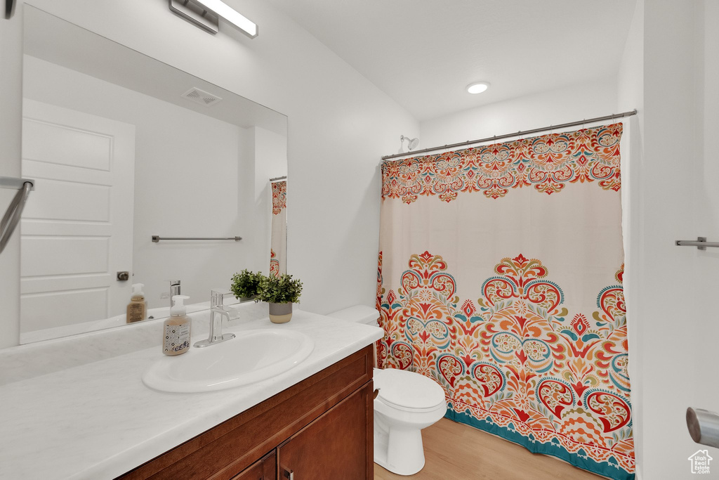Full bathroom featuring vanity, curtained shower, and wood finished floors