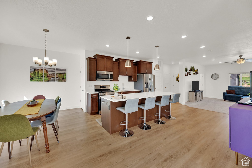 Kitchen featuring stainless steel appliances, a chandelier, light countertops, a kitchen breakfast bar, and light wood-style floors