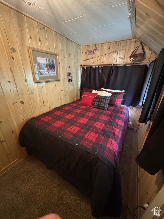 Bedroom featuring wood walls, lofted ceiling, and carpet