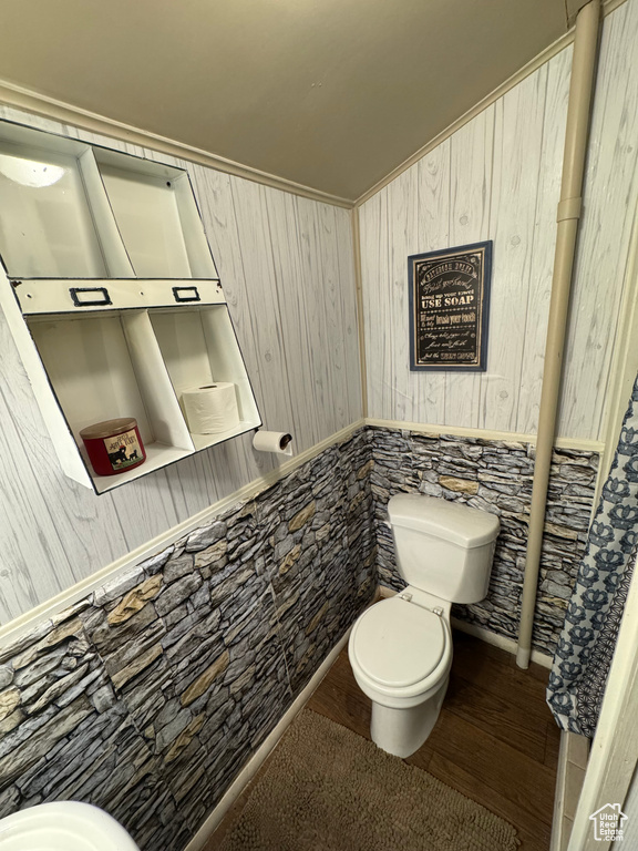 Half bath with wood finished floors and wood walls