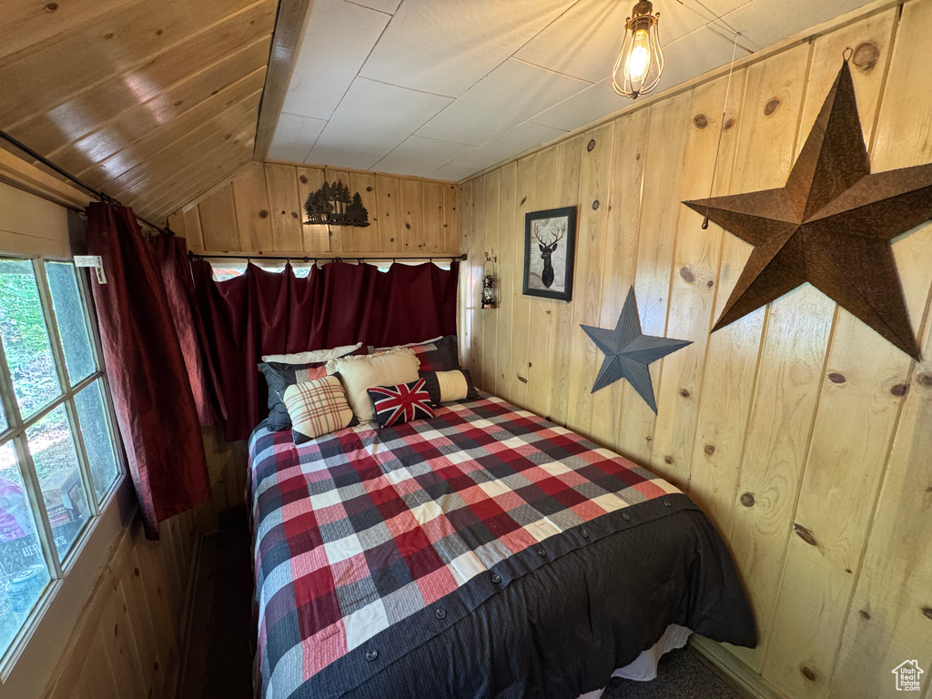 Bedroom featuring wood walls, vaulted ceiling, and carpet