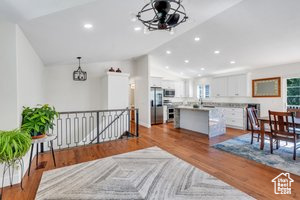 Living area featuring lofted ceiling, a chandelier, wood finished floors, and recessed lighting