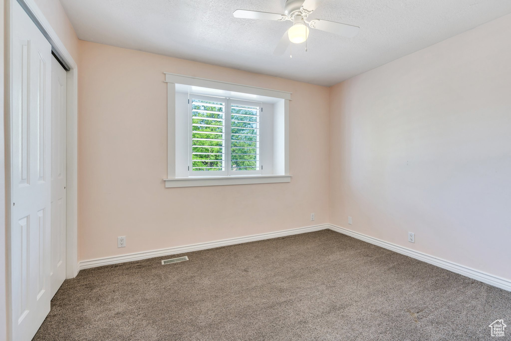 Unfurnished bedroom featuring carpet flooring, a closet, a ceiling fan, and a textured ceiling
