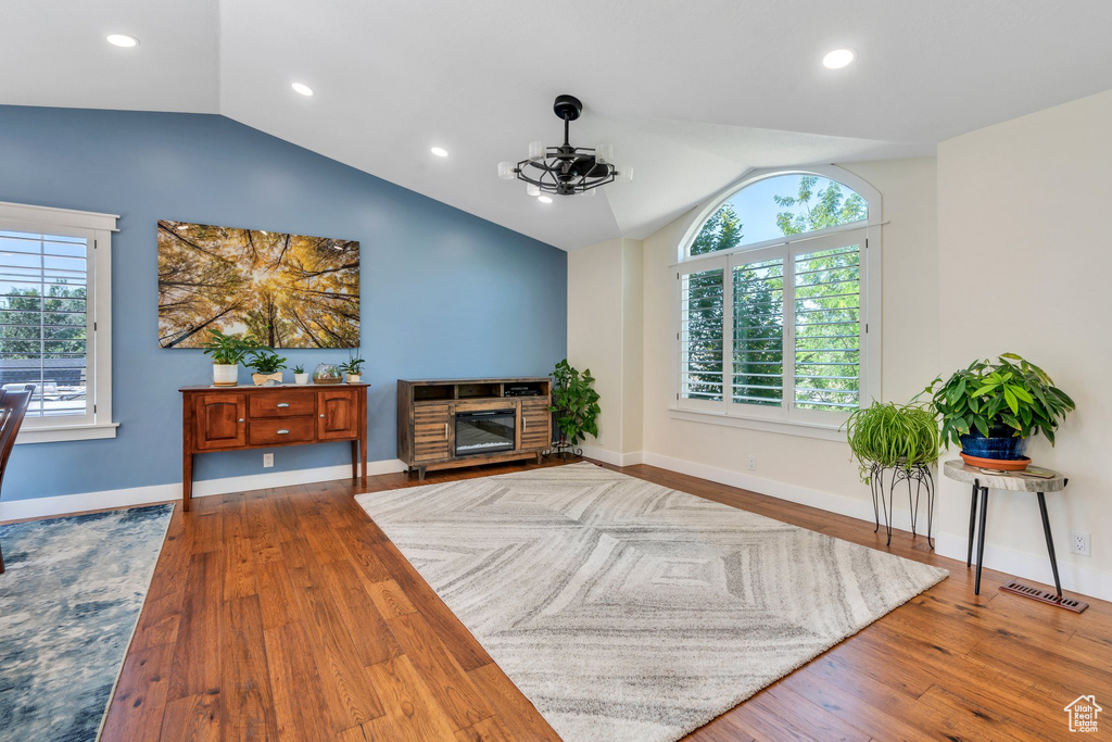 Living room featuring vaulted ceiling, wood-type flooring, recessed lighting, and a glass covered fireplace