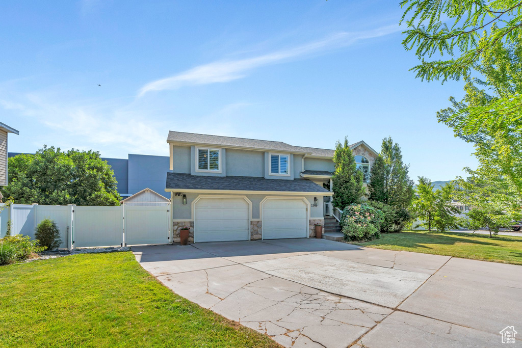 View of front of home featuring a gate, stucco siding, stone siding, concrete driveway, and an attached garage