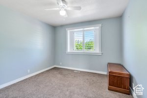 Carpeted empty room with ceiling fan and baseboards