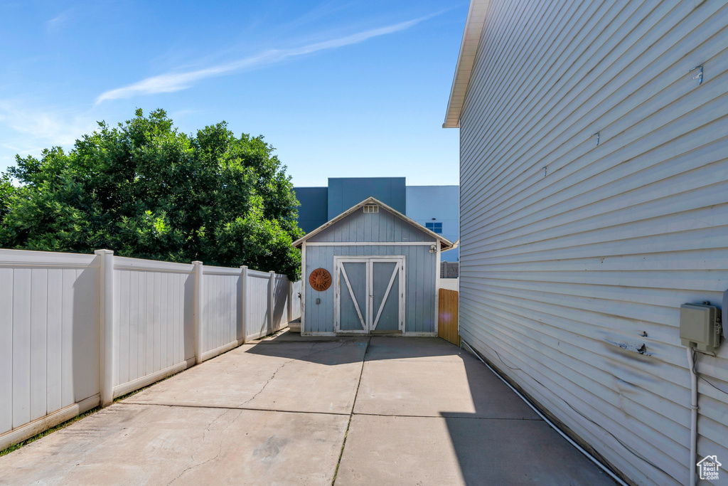 Fenced backyard featuring a shed and a patio area