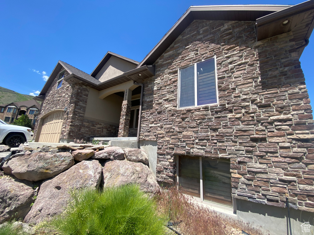 View of home\'s exterior with stone siding, an attached garage, and stucco siding